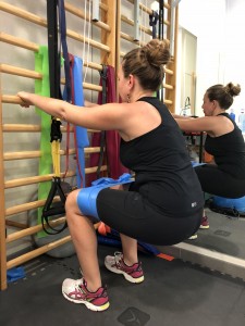 Sentadillas en fase inicial para favorecer el control del equilibrio, con banda elástica de resistencia para mayor activación glútea